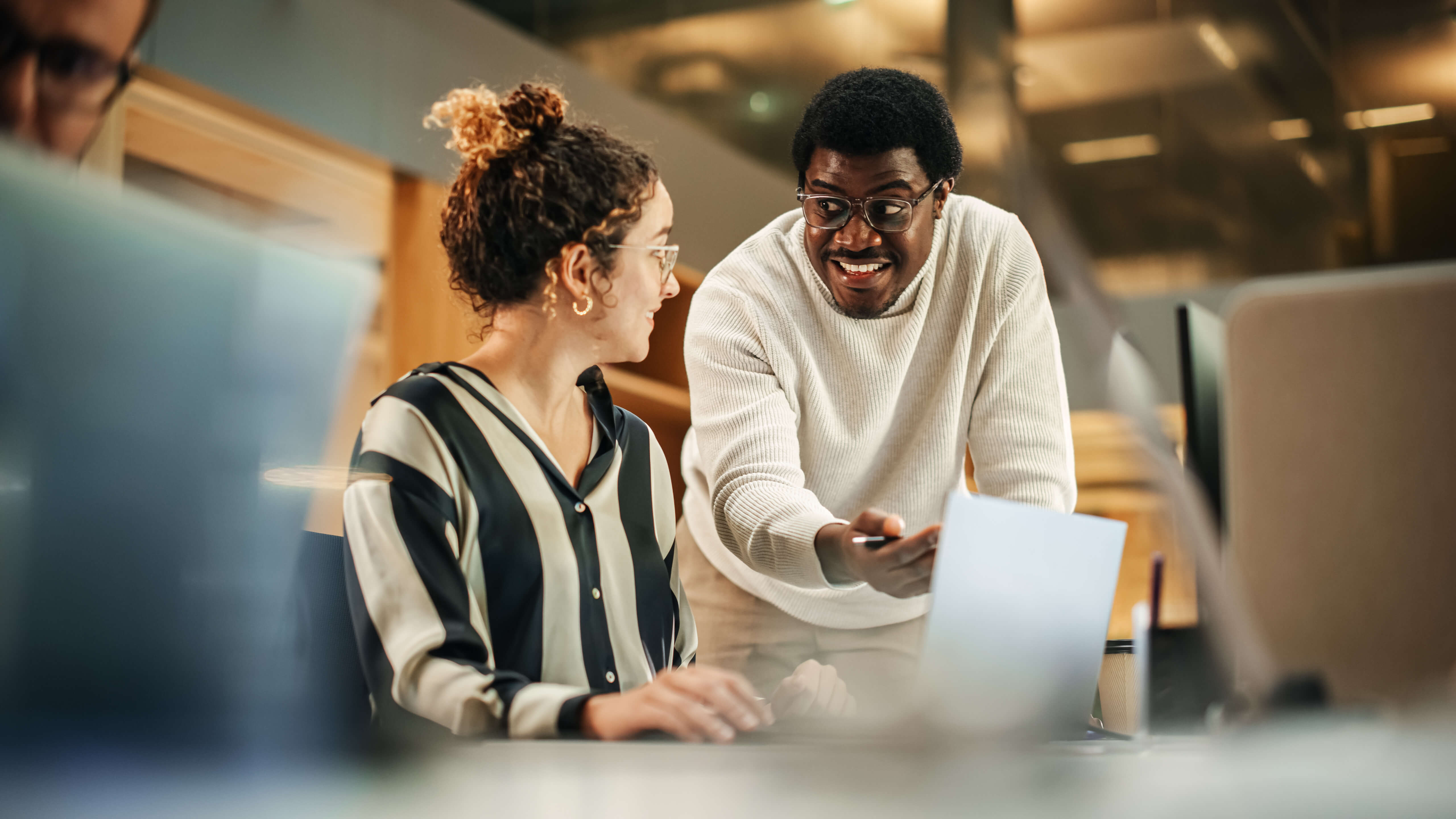 Two people working on a computer looking at each other.